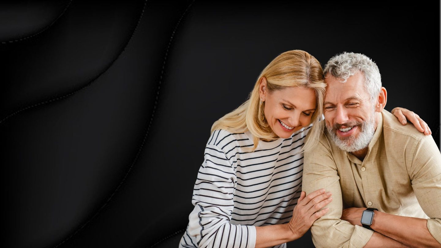 Pareja mayor sonriendo, apoyada el uno en el otro